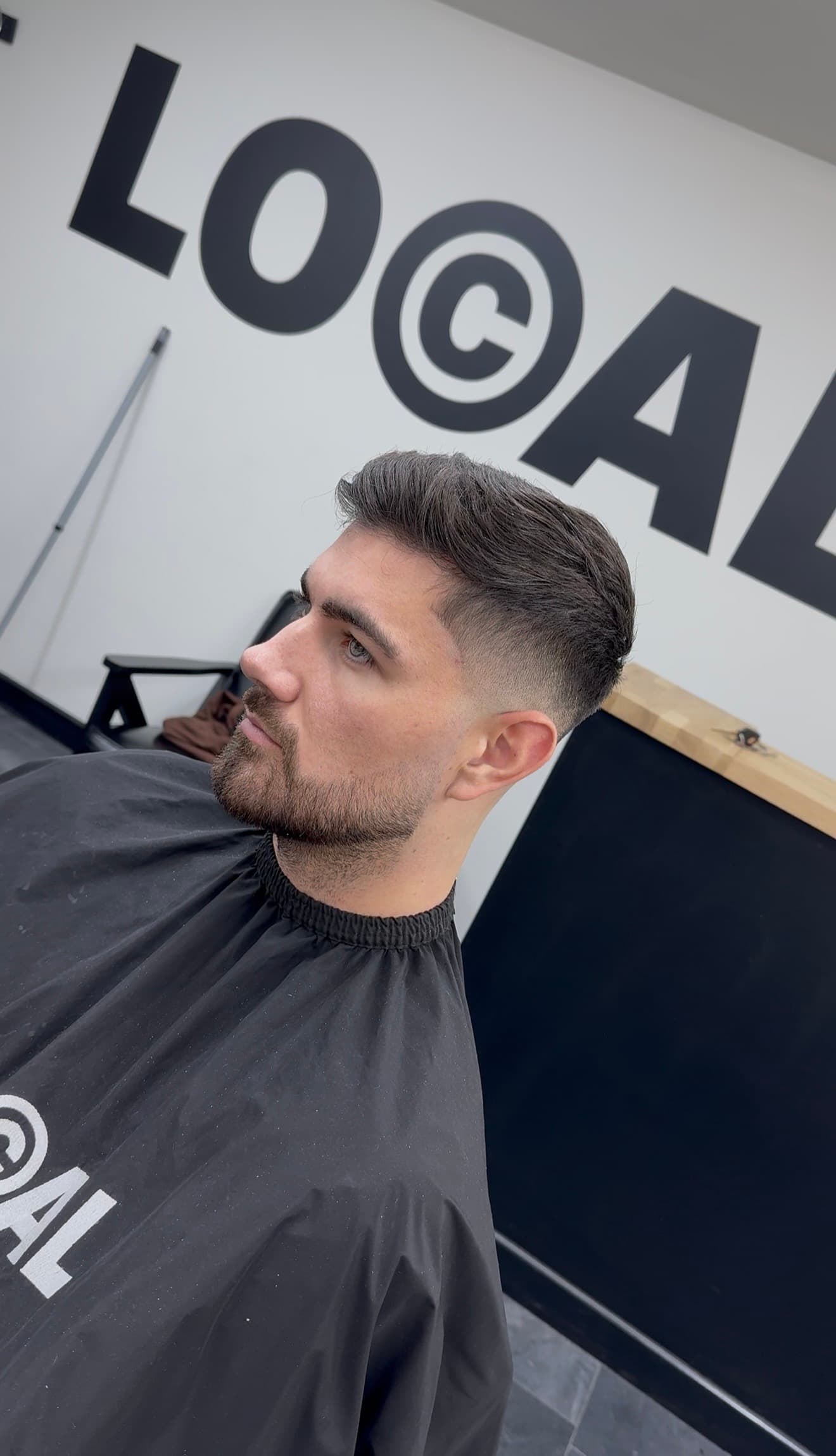 Side profile of a man with a fresh skin fade haircut and groomed short beard.