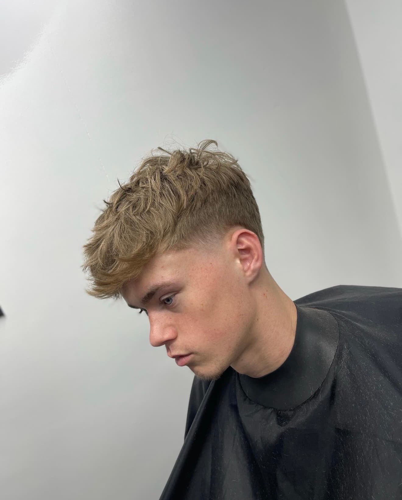 Side profile of a young man with a textured crop haircut and skin fade.